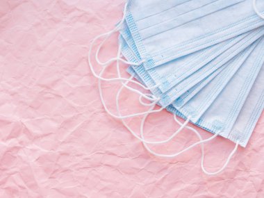 Mavi koruyucu tıbbi maske sürüsünün üst görüntüsü. Coronavirus COVID-19 pembe buruşmuş arkaplan ve fotokopi alanı kavramı.