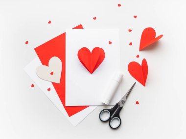 Sevgililer Günü ya da Anneler Günü tebrik kartı. Kırmızı kağıt hacimsel kalp ile DIY tatil kartı, aşk ve romantizmin sembolü. Makas, yapıştırıcı ve renkli kağıtlardan yapılmış el yapımı bir kart..