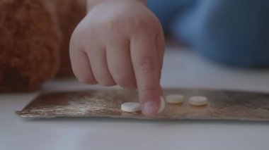 Çocuk ilaç dağıtarak oynuyor. Bebek, ebeveyn kontrolü olmadan haplara dokunuyor. Tehlikeli bir durum..
