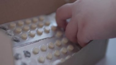 Çocuk ilaç dağıtarak oynuyor. Bebek, ebeveyn kontrolü olmadan haplara dokunuyor. Tehlikeli bir durum..