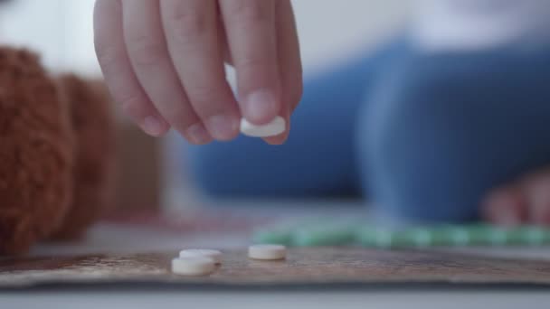 El chico juega con medicamentos dispersos. El niño toca las pastillas sin el control de los padres. Situación peligrosa . — Vídeo de stock