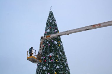 A worker decorates a Christmas tree in Volgograd clipart