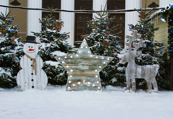 Muñeco de nieve de madera, estrella con luces y ciervos — Foto de Stock