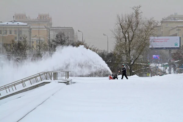 Trabajador limpia nieve de aceras con soplador de nieve en Moscú —  Fotos de Stock