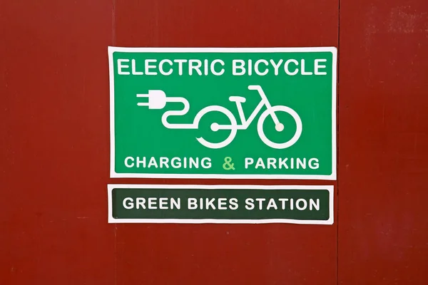 Таблица "Электрическая зарядка и парковка велосипедов" и "Зеленая станция велосипедов" на красном фоне — стоковое фото