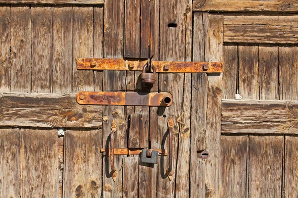 Old brown wooden door with rusty handles and locks — Stock Photo, Image