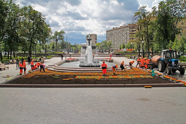 Les travailleurs plantant des bégonias rouges dans le lit de fleurs sur la place Pouchkine à Moscou — Photo