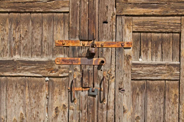 Old brown wooden door with rusty handles and locks — Stock Photo, Image