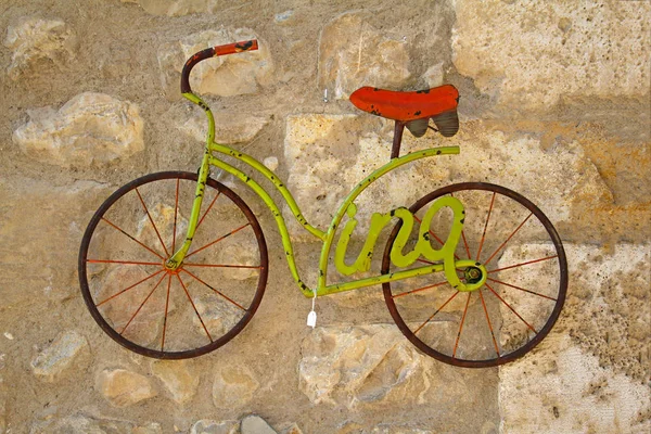 Декоративная зеленая модель велосипеда висит на каменной стене для продажи на рынке Бесалу — стоковое фото