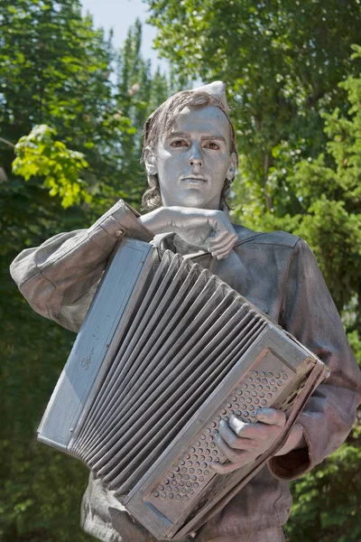 Zilveren beschilderde kunstenaar met accordeon verkleed als Russisch Sovjet-soldaat van de Tweede Wereldoorlog op een stad straat — Stockfoto