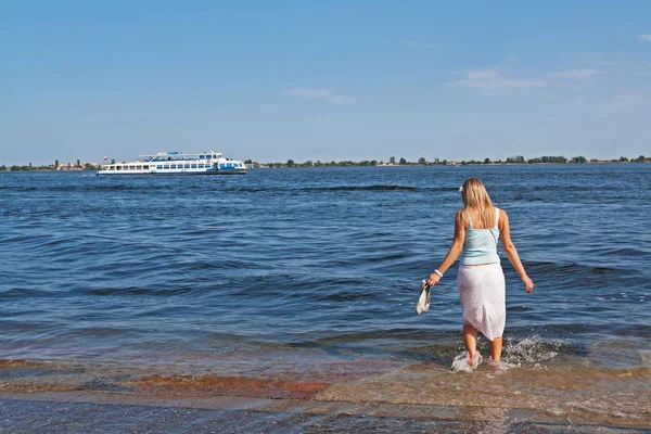 Mulher loira remando seus pés descalços durante uma inundação no fundo do rio Volga com um barco — Fotografia de Stock