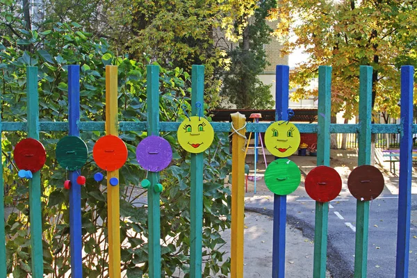 Homemade children's art object in the form of a caterpillar on a fence of multi-colored circles, wire and bottle caps — Stock Photo, Image