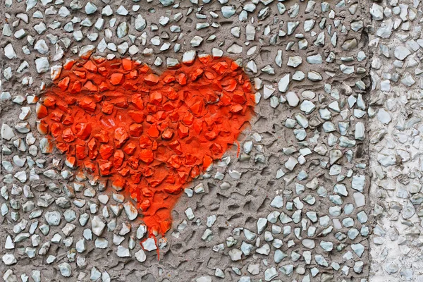 Red heart on wall of small stones as background, texture