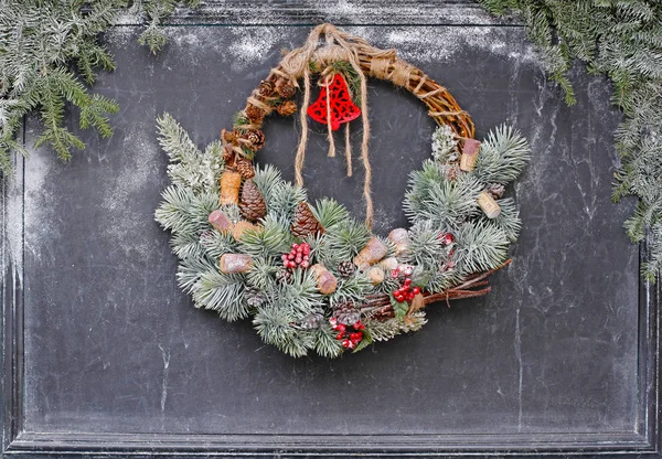 Christmas wreath hanging on a black chalk board