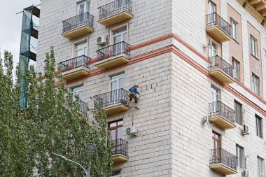 Volgograd, Rusya - 27 Eylül 2019: Volgograd 'da bir apartmanın cephesini yeniden inşa eden inşaat işçisi