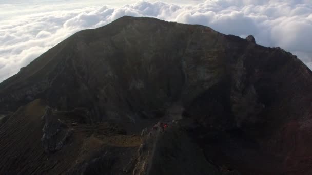 Un grupo de turistas de pie en el borde del cráter del volcán Agung en Bali, Indonesia (video aéreo ) — Vídeos de Stock