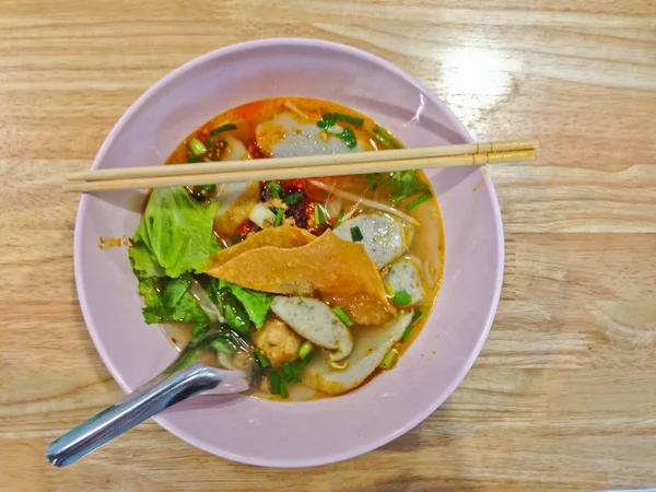 Nudel Tom Yum mit Schweinefleisch / würzige thailändische Nudeln auf Holztisch — Stockfoto