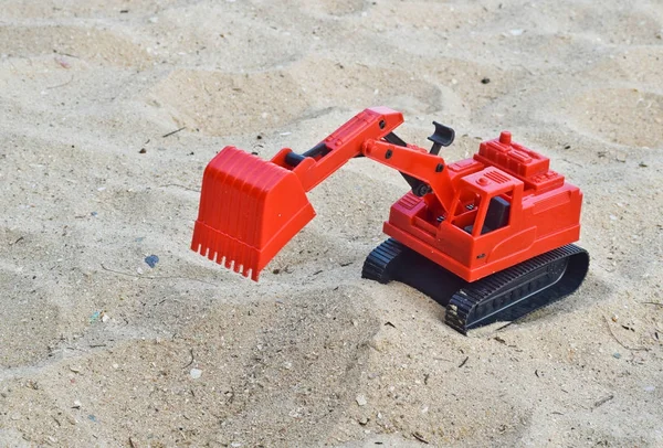 Детская игрушка красный экскаватор автомобиль на песке, промышленные символы — стоковое фото