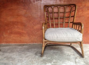 Kahverengi duvar ile beton zemin üzerinde Rattan Koltuk 