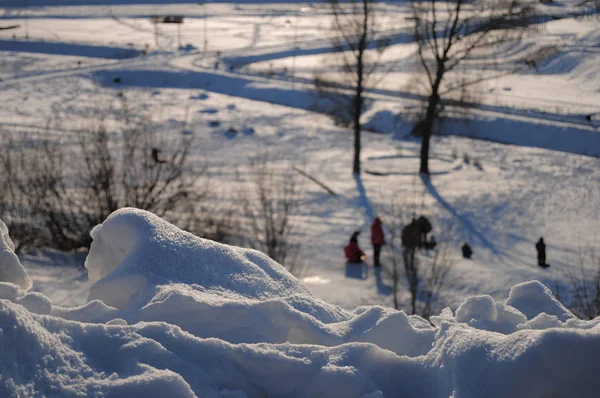 Snow-white snowdrifts. Children slide down the hill In the backg — Stock Photo, Image