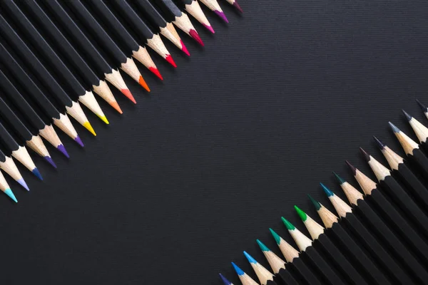 Creative minimal backdrop. Colored pencil set arranged on black background, copy space