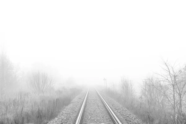 Железнодорожный путь исчезает в тумане — стоковое фото