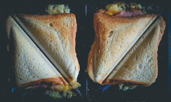 Toasts with ham and cheese toasted into triangles on toaster