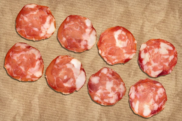 Varkensvlees Salami segmenten op verfrommeld gestreepte Manilla bruin kraftpapier — Stockfoto