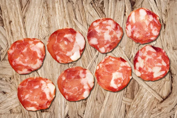 Varkensvlees Salami segmenten op houten spaanplaat Grunge achtergrond — Stockfoto
