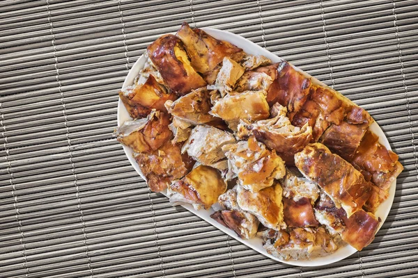 Plateful of Spit Roasted Pork Slices On Straw Place Mat — Stock Photo, Image