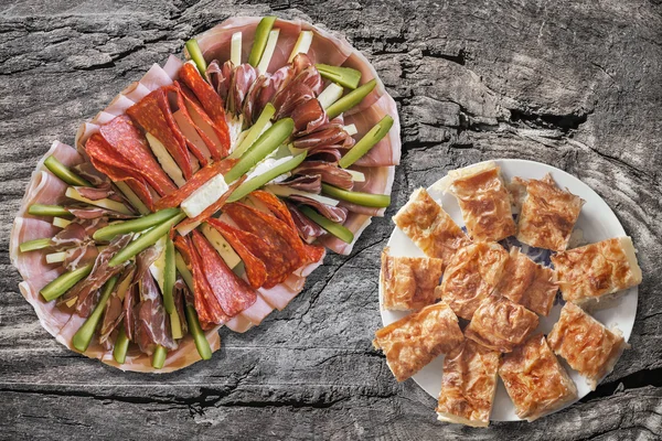 Voorgerecht smakelijke schotel Meze met bord van Servische traditionele Gibanica verfrommeld kaas Pie Set op oude gebarsten houten picknicktafel — Stockfoto