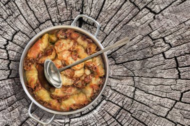 Paslanmaz çelik Saucepot küme eski kırık güdük üzerinde füme jambon dilimleri ile domates sosu ile kıyılmış et dolması lahana rulo pişmiş