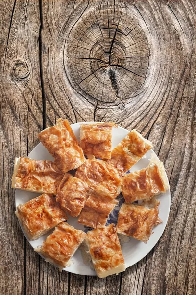 Plateful de serbio tradicional arrugado queso empanada rebanadas conjunto sobre la vieja mesa de madera Picnic agrietado anudado — Foto de Stock