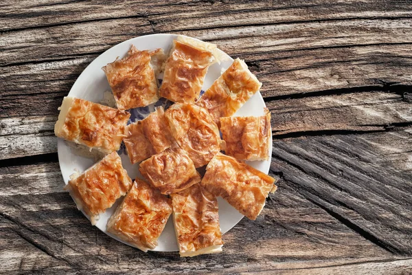 Sırp geleneksel buruşuk peynir pasta dilimleri sette eski ahşap düğümlü kırık piknik masası tabak — Stok fotoğraf