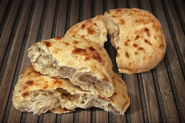 Szakadt két Pitta kenyeret Loafs meg a régi, fából készült tányéralátét — Stock Fotó