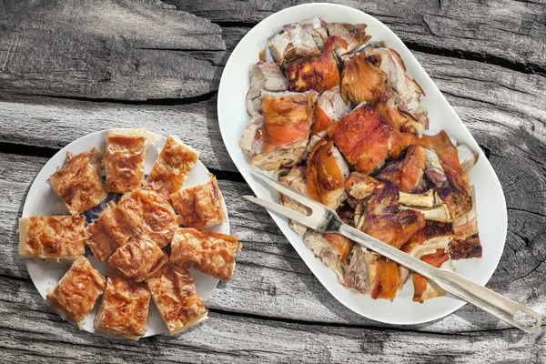 Plateful de asador asado rebanadas de hombro de cerdo y queso arrugado serbio pastel Gibanica conjunto sobre la vieja mesa de Picnic madera nudo rústico — Foto de Stock