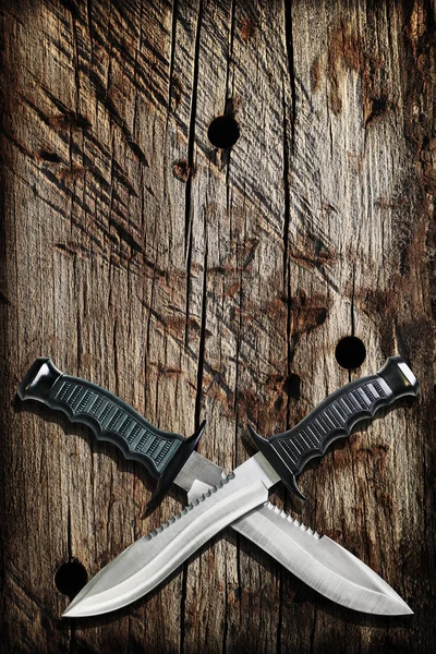 Cuchillos Bowie tácticos de la supervivencia de la caza del combate con las cuchillas cruzadas en Grunge Viñetted viejo maltrecho acanalado fondo de madera — Foto de Stock