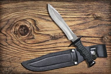 Hayatta kalma Sawback Bowie bıçak siyah deri kılıf seti ile eski kırık düğümlü rustik Pinewood arka planda av mücadele