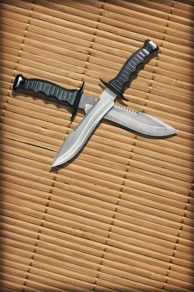 Тактические боевые охотничьи ножи Боуи со скрещенными лезвиями на разрезанном сельском бамбуковом месте — стоковое фото