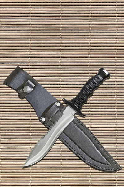 Couteau Bowie Sawback à lame fixe tactique de chasse au combat avec gaine en cuir noir sur fond de tapis de place en bambou rustique à lattes — Photo