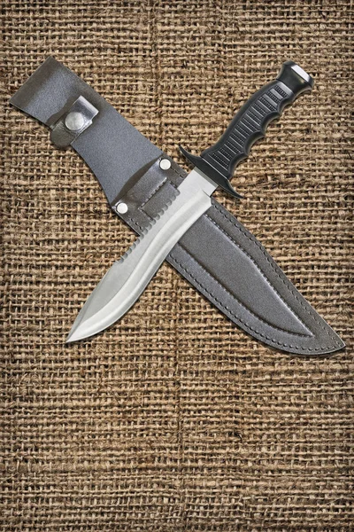 Fixed Blade Tactical Combat Hunting Survival Sawback Bowie Knife With Black Leather Sheath Set On Coarse Grain Burlap Vignette Grunge Backdrop
