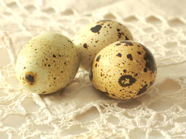 Three quail eggs on lace tablecloth — Stock Photo, Image