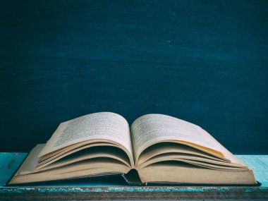 Tahta bir masada eski bir kitap açılıyor.
