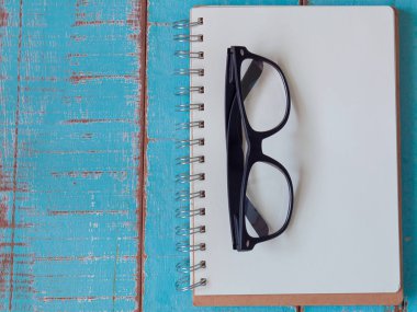 defter ve ahşap zemin üzerinde gözlük.