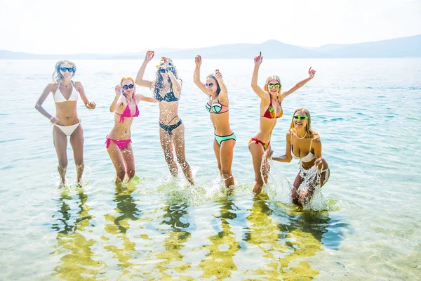 年轻的一群妇女在日落时分在海里跳跃 在水中跳跃的成年女孩队 — 图库照片