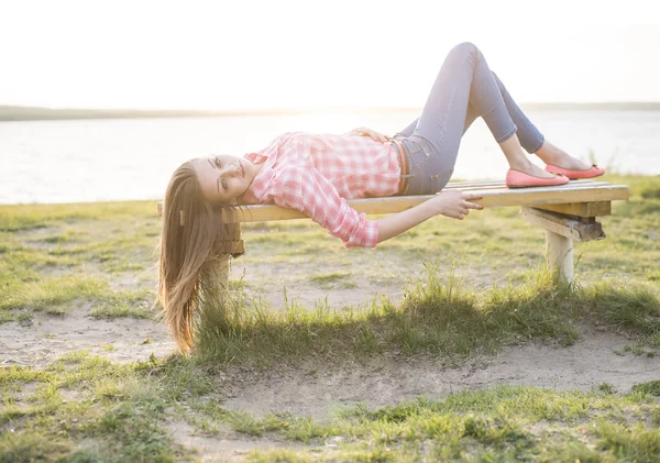 Молодая женщина лежит на деревянной скамейке — стоковое фото
