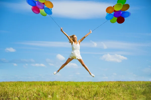 Žena Jumping s barevnými balónky — Stock fotografie