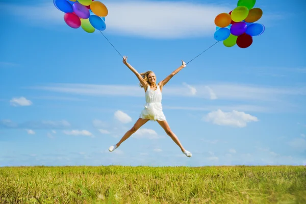 Mujer saltando con globos de colores — Foto de Stock