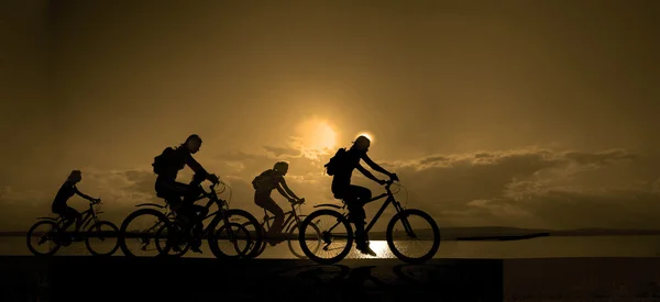 Темные силуэты спортивных друзей на велосипедах — стоковое фото
