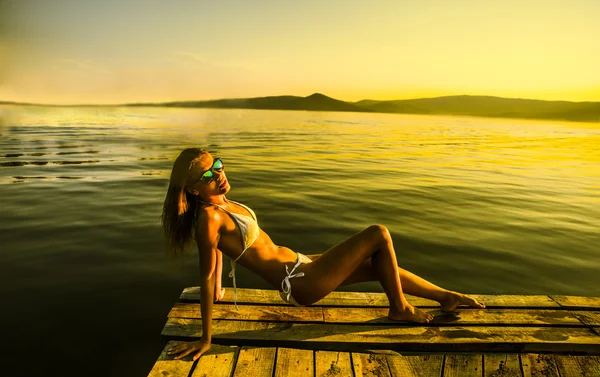 Vrouw in bikini op de houten taart — Stockfoto